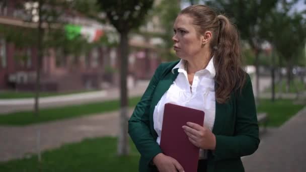 Retrato de la mujer de negocios caucásica obesa cansado de pie con el ordenador portátil en el pensamiento de la calle de la ciudad. Triste adulto hermosa mujer de tamaño grande en traje formal esperando al aire libre. Concepto de negocio y estilo de vida. — Vídeos de Stock