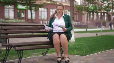 Geniş açılı portre özümsenmiş profesyonel kadın analist kentteki bankta oturmuş evrak işlerini inceliyor. Uzman Kafkas aşırı kilolu kadın dışarıda iş stratejisi planı yapıyor..