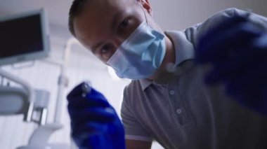 Ağız aynası ve diş sondası olan hasta POV dişçisi dişleri yavaş çekimde inceliyor. Diş sağlığını kontrol eden beyaz uzman bir adamın portresi. Ortodonti konsepti.