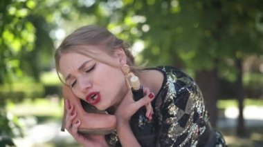 Yorgun ve sarhoş genç bir kadın ayakkabıyla konuşuyor. Sabahları dışarıda şişeden şarap içiyor. Şehir parkındaki sarhoş beyaz kadının partiden sonra alkolle çekilmiş portresi..