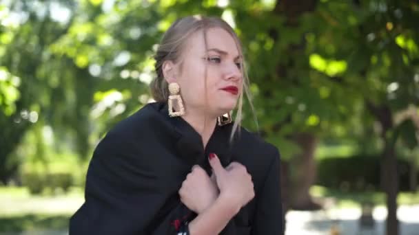 Medium shot dissatisfied young drunk woman sitting in sunrays in park looking around. Irritated tired Caucasian slim beautiful party-goer in sunshine outdoors thinking. Hangover and tiredness. — Stock Video