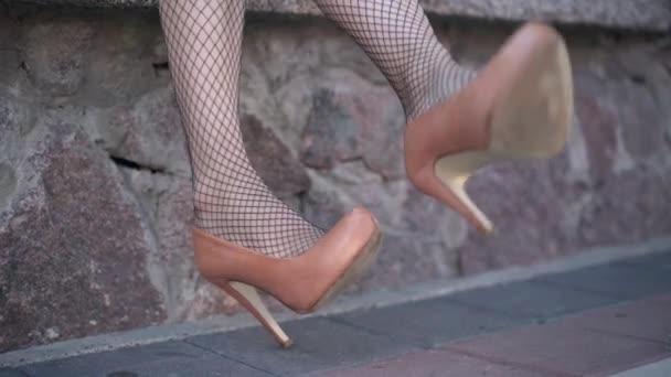 Jambes femelles minces en bas résille décollant les talons hauts marron à l'extérieur. Jeune femme caucasienne méconnaissable dans des chaussures inconfortables dans la ville urbaine. Concept de style de vie et de féminité. — Video