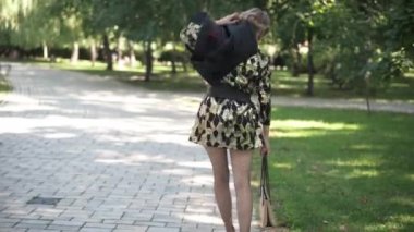 Parti elbisesi ve yüksek topuklu ayakkabı giyen sarhoş, beyaz bir kadın şehir parkında güneşli bir sabahta yürüyor. Milenyum partilerine katılan şaşırtıcı bir şekilde açık havada geziniyor..