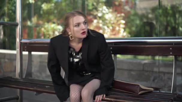 Tired party-goer sitting on bus stop rushing leaving purse returning for bag and running away. Hurrying Caucasian young slim beautiful woman catching transport after partying. — Stock Video