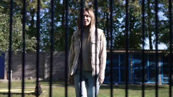 Dog POV cheerful young beautiful woman approaching to cage talking smiling in slow motion. Portrait of kind empathetic Caucasian lady choosing pet in animal shelter outdoors on sunny day. — Stock Video