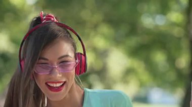 Canlı kamera, 1990 'larda yaz parkında, pembe güneş gözlüklü neşeli genç bir bayanı, el sıkışarak dans ederken izliyor. Neşeli, kaygısız, beyaz bir kadının açık havada eğlenen portresi.