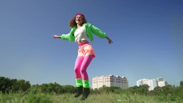 Large plan femme joyeuse dans des vêtements rétro sautant en dansant en plein air en plein soleil. Portrait d'excitée heureuse dame caucasienne insouciante ayant plaisir à écouter de la musique disco. Bonheur et loisirs. — Video