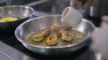 Yakından çekilen yağlar, yavaş çekimde ızgara karideslerle pişirme tavasında tutuşturur. Tanımlanamayan profesyonel Kafkasyalı aşçı restoran mutfağında lezzetli deniz ürünleri pişiriyor..