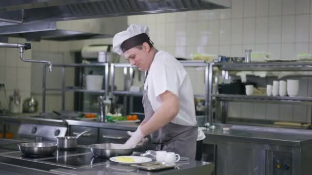 Portrait de cuisinier masculin en uniforme nettoyant les ustensiles de cuisine dans la cuisine du restaurant à l'intérieur. Homme caucasien professionnel positif travaillant souriant. Concept culinaire et gastronomique. — Video