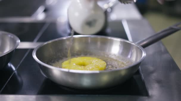 Primo piano cuoco irriconoscibile versando acqua in padella friggendo l'ananas al rallentatore. Maschio mano caucasica in guanto aggiungendo liquido in stoviglie con frutta. Concetto culinario e cucina. — Video Stock
