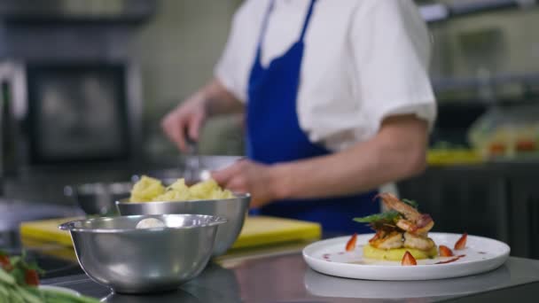 Mariscos cocidos e ingredientes crudos en la cocina comercial con cocinero masculino irreconocible mezclando en cámara lenta en el fondo. Concepto culinario y gastronómico. — Vídeos de Stock