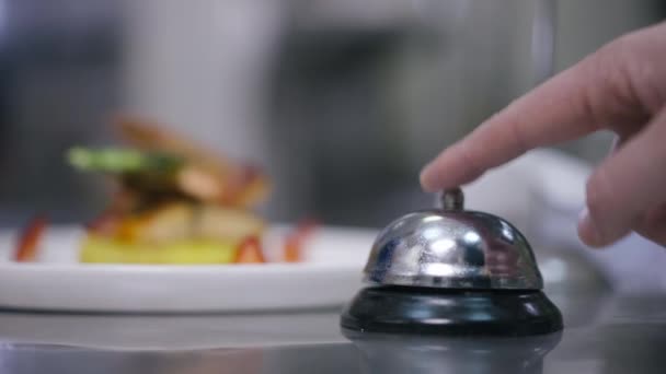Close-up male finger pushing service bell ringing and hands taking away plate with delicious seafood in restaurant kitchen. Unrecognizable cook and waiter passing order indoors. Service and culinary. — Stockvideo