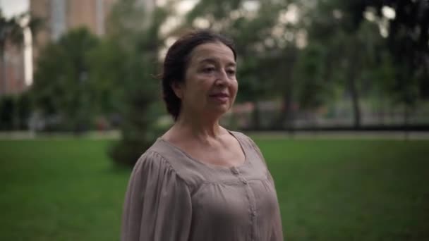 Side view gorgeous senior Caucasian woman strolling in park with shopping bags smiling. Tracking shot portrait of beautiful lady satisfied with purchases walking outdoors. Lifestyle and retirement. — Vídeo de stock