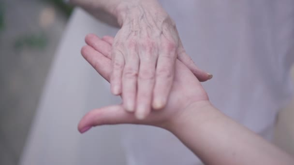 Close-up young and senior Caucasian women stacking hands in slow motion outdoors. Unrecognizable grandmother and granddaughter enjoying weekend leisure on spring summer day. Family concept. — Stok video