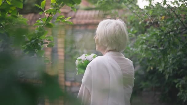 Back view senior woman in wedding dress turning looking at camera smiling posing in sunrays outdoors. Portrait of happy elegant confident Caucasian retiree getting married looking at camera smiling. — Vídeo de stock