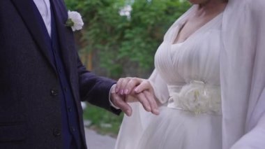 Tanımlanamayan kıdemli gelin ve damat dışarıda ağır çekimde el ele tutuşuyorlar. Mutlu beyaz çift düğün gününde el ele tutuşuyor. Aşk ve keyif.