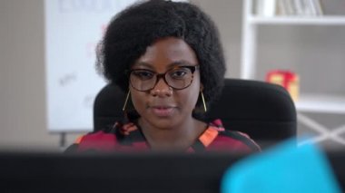 İnternette gülümseyen kendine güvenen Afro-Amerikan bir kadının ön görüntüsü. Ofiste çalışan başarılı bir yöneticinin portresi. Yavaş çekim.