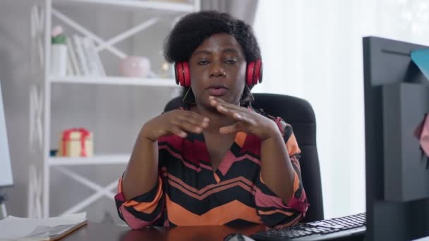 Chat vidéo POV de femme afro-américaine confiante dans un casque parlant au ralenti. Portrait de intelligent jeune freelance conférence en ligne dans le bureau à domicile à l'intérieur. — Video