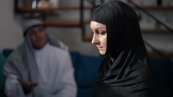 Retrato de vista lateral de la mujer estresada de Oriente Medio molesta en hijab negro mirando hacia otro lado pensando como hombre hablando gesto en segundo plano. Triste hermosa esposa en casa con el marido discutiendo peleas. — Vídeos de Stock