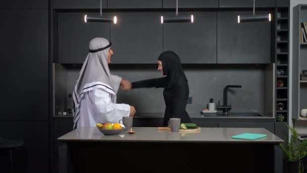 Radosna kochająca się para z Bliskiego Wschodu tańcząca w kuchni w domu i śmiejąca się. Szczęśliwy mężczyzna przędzenia kobieta dobrze się bawić w weekend razem w pomieszczeniach. Koncepcja relacji i wspólnoty. — Wideo stockowe