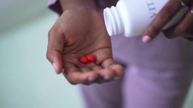 Turuncu vitamin haplı Afrika kökenli Amerikalı kadın avuç içi. Evde ilaç takviyeleriyle tanınmayan genç, sıska bir kadın var. Tıp ve güzellik konsepti.