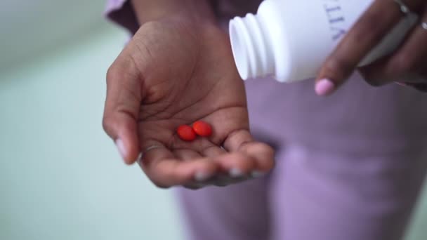 Close-up vrouwelijke Afro-Amerikaanse palm met oranje vitaminepillen. Onherkenbare jonge slanke vrouw binnen met medicijnen supplementen. Geneeskunde en schoonheidsconcept. — Stockvideo