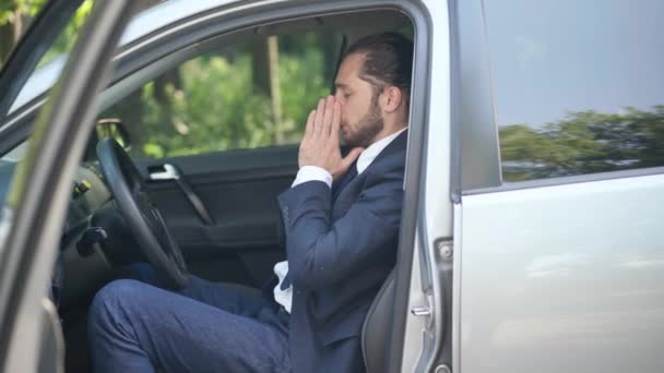 정장을 입은 젊은 백인 남자 가 밖에 앉아 있는 운전석에서 재채기와 기침을 하고 있었다. 운전을 제대로 못 하고 호흡기 질환 이 있는 남자 운전자의 모습. 코로나 바이러스 대유행 개념. — 비디오