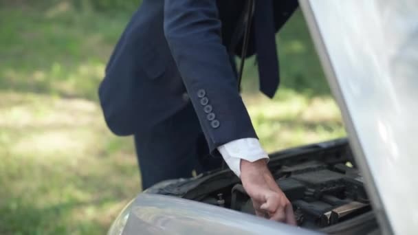 Uomo irriconoscibile che controlla il motore nel cofano di un'auto aperta nella giornata di sole all'aperto. Autista caucasico che ripara un veicolo rotto sul ciglio della strada. Concetto di incidente stradale. — Video Stock