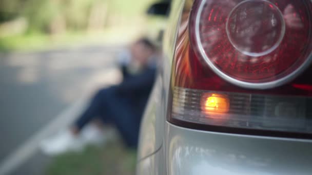 Lumini de închidere a mașinii cu șofer încețoșat așezat la un vehicul spart în fundal. Farul din spate auto aprins și trist caucazian stresat om de așteptare pentru ajutor de asigurare. — Videoclip de stoc