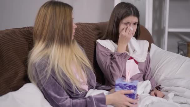 Depresyonda olan genç bir kadın, elinde kağıt mendille kanepede oturmuş destek arkadaşı olarak ağlıyor. Kırık kalpli beyaz bir bayanın orta boy portresi. Evinde oyalanıyor.. — Stok video