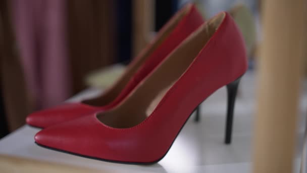 Zbliżenie czerwony stylowe wysokie obcasy z męską białą ręką biorąc obuwie pozostawiając w zwolnionym tempie. Nierozpoznany gej wybierający buty w modnym sklepie w domu. Wybór i moda. — Wideo stockowe