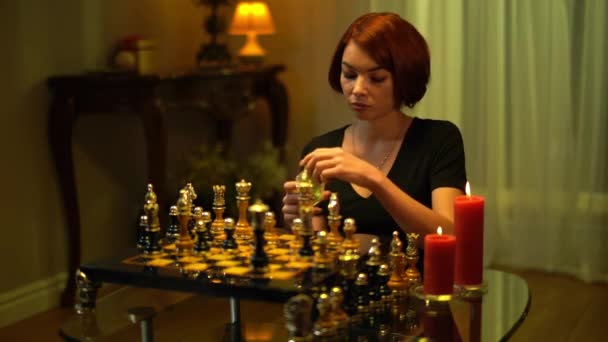悲しい不満を持つ女性が手にチェスボードに屋内に座って薬を注ぐ。イライラの肖像不確定な白人の赤毛のチェスの選手は薬を考えて。中毒と知性. — ストック動画