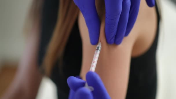 Close-up injectie van het coronavirusvaccin in slanke vrouwelijke blanke hand. Onherkenbare verpleegkundige die Covid-19 injecteert genezing behandeling in arm van jonge vrouw in vaccinatiecentrum of kliniek binnen. — Stockvideo