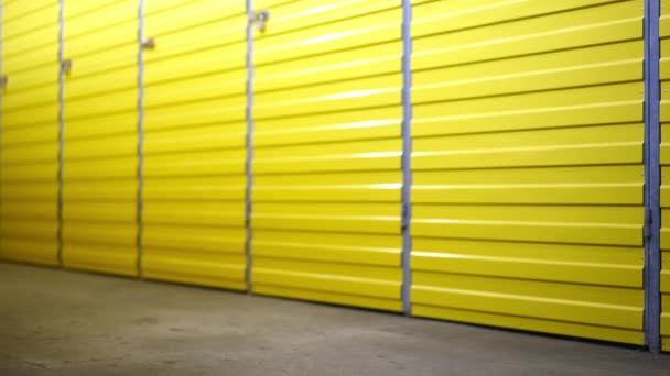 Row of yellow storage rooms doors with legs of young woman passing pushing trolley. Unrecognizable female tenant walking in warehouse self storage indoors leaving. — Stock Video