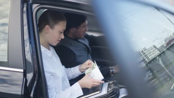 Boční pohled portrét štíhlé mladé krásné ženy počítání peněz sedí v autě s rozmazaným mužem. Kavkazský koncentrovaný průmyslový špion s úplatkem od obchodníka v centru města. — Stock video