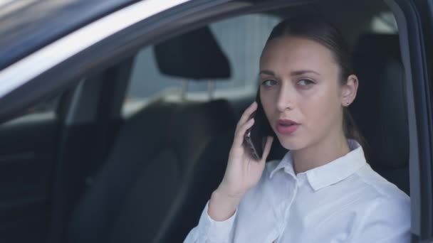 Pensativo ocupada joven empresaria hablando por teléfono sentado en el asiento del conductor en el coche. Retrato de una hermosa mujer caucásica seria discutiendo la estrategia de planificación del pensamiento de ideas. Estilo de vida urbano. — Vídeo de stock