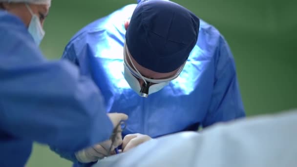 Chirurgien expert opérant patient sur lit chirurgical avec infirmière nettoyage dissection au ralenti. Portrait d'un homme et d'une femme professionnels de race blanche travaillant à l'hôpital à l'intérieur. Concept médical. — Video