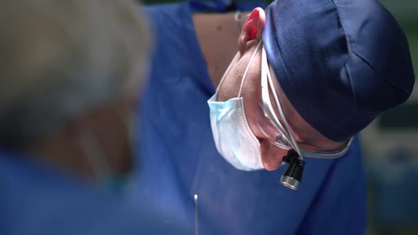 Крупным планом сконцентрирован Кавказский пластический хирург, выполняющий лицевую операцию в клинике в помещении. Портрет уверенного в себе профессионального врача со скальпелем, делающего вскрытие блефаропластики. — стоковое видео