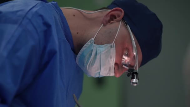 Pewny siebie chirurg plastyczny wykonujący kauterie podczas operacji blepharoplastyki rozmawiający z pielęgniarką w zwolnionym tempie. Widok z boku portret skoncentrowanego poważnego mężczyzny rasy kaukaskiej w mundurze wykonującego operację powiek. — Wideo stockowe