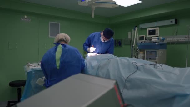 Brett operationsrum med professionell läkare och sjuksköterska som utför ansiktskirurgi i slow motion. Expert kaukasiska man och kvinna som arbetar på kliniken gör plastikkirurgi inomhus. — Stockvideo