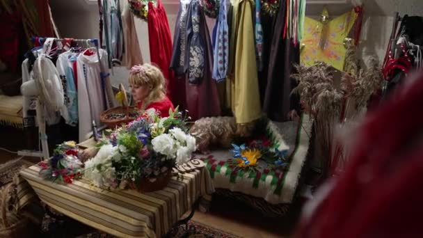 Amplia tiro ropa tradicional ucraniana en el interior con talentosa persona artesanal haciendo corona de la cabeza en cámara lenta. Señora atractiva y segura en vestido nacional con bordado disfrutando de la artesanía. — Vídeo de stock