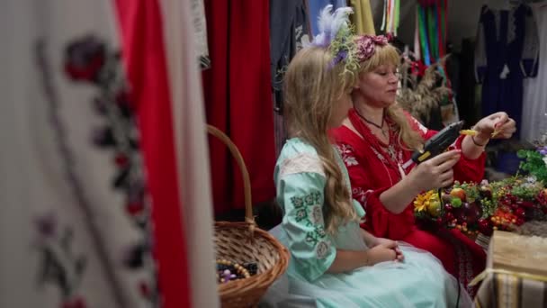 측면에서는 숙련 된 우크라이나 여성 이 공예 상점에서 전통적으로 머리에 화환을 만드는 퀴리 오스 소녀와 이야기하는 것을 본다. 재능있는 어머니는 집안에서 느린 동작으로 딸을 가르친다. 생활 방식 과문 화. — 비디오