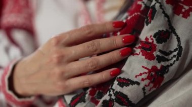 Geleneksel Ukrayna siyah ve kırmızı işlemeli manikürlü ince kadın eli ağır çekimde. Tanımlanamayan, kendine güveni olan genç bir kadın ulusal elbisesini içeride okşuyor. Kültür ve milliyet.