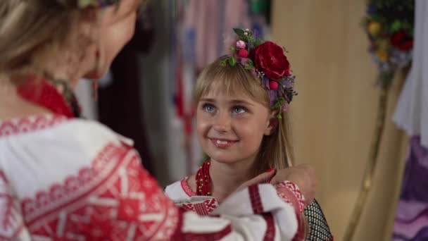 Πορτρέτο του χαριτωμένο παιδί της Ουκρανίας χαμογελώντας κοιτάζοντας τη γυναίκα πλέξιμο μακριά μαλλιά σε αργή κίνηση. Η όμορφη κόρη θαυμάζει τη μητέρα που φροντίζει το παιδί. Πυροβολισμοί πάνω από ώμο. — Αρχείο Βίντεο