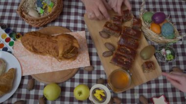 Paskalya yemeği ve beyaz kadın ellerinin lezzetli tatlı seçtiği üst manzara masası. Tanınmayan aile, tatilde evde lezzetli yemekler yiyor. Mutluluk ve kutlama konsepti.