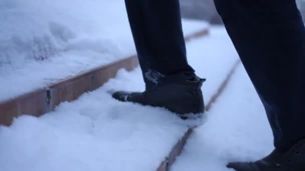 Câmera ao vivo segue passos de pés masculinos andando lá em cima ao ar livre. Homem irreconhecível em sapatos de couro preto passeando no alpendre no quintal ou quintal no dia de inverno nevado. — Vídeo de Stock