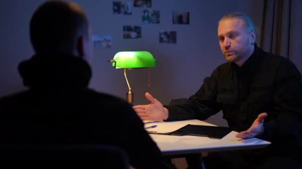 Pohledný bělošský policajt si potřásá rukou, když si muž povídá uvnitř. Portrét sebevědomého detektiva a informátora ve tmě, který sdílí informace. Koncept vyšetřování a tajné služby. — Stock video