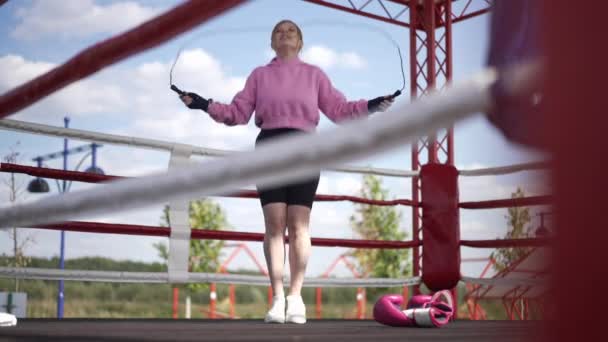 ワイドショットは、ボクシングリング上のスローモーションでロープをジャンプ動機付け白人スポーツ女性。自信に満ちたインスピレーションを受けた女性のフロントビューの肖像画日光屋外でトレーニングを行っています。スポーツコンセプト. — ストック動画