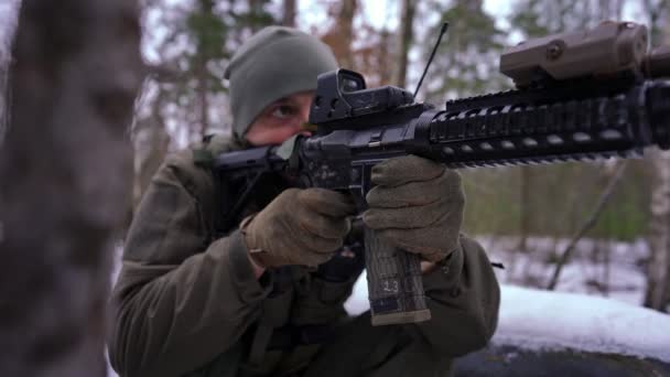 Broń zbliżeniowa z młodym człowiekiem strzelającym w zwolnionym tempie na zewnątrz. Uzbrojony poważny ukraiński żołnierz walczący w strefie wojny w zimowym lesie. Koncepcja inwazji wojskowej i obrony. — Wideo stockowe