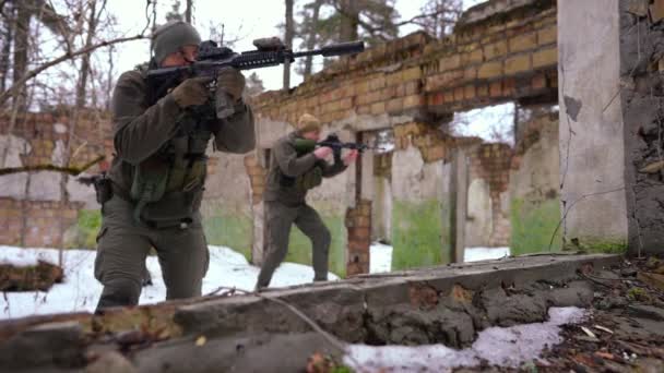 Een groep jonge gewapende mannen en vrouwen die zich in slow motion verstoppen in een verwoest gebouw. Portret van geconcentreerd Kaukasisch slagbal buiten op koude winterdag. — Stockvideo